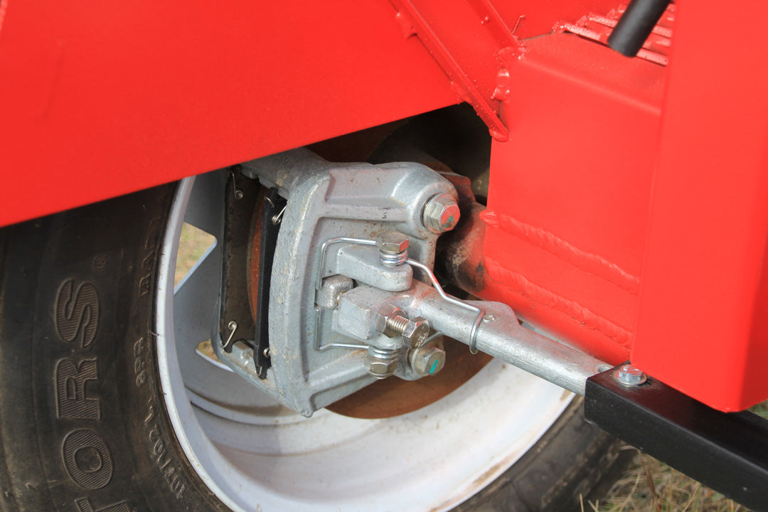 A close up view of the left-hand side mechanical disc brake assembly attached to a pneumatic tire on a red forecart. 